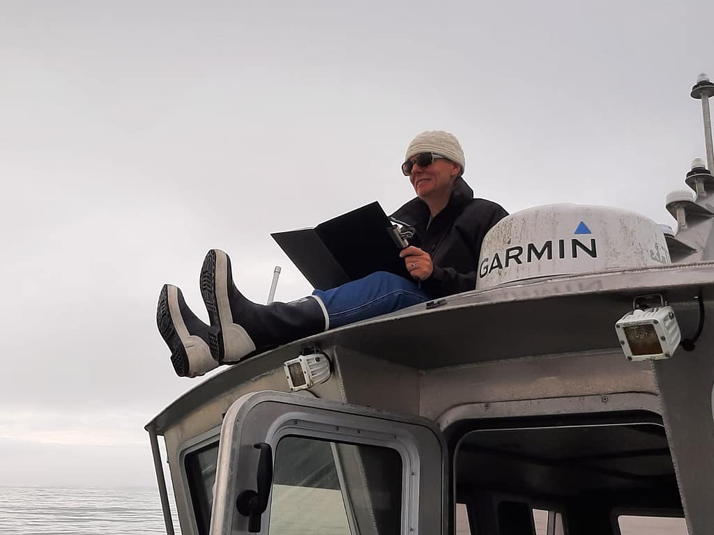 Biography Artist Rosanne Guille painting whilst sat on top of an Alaskan fishing boat.